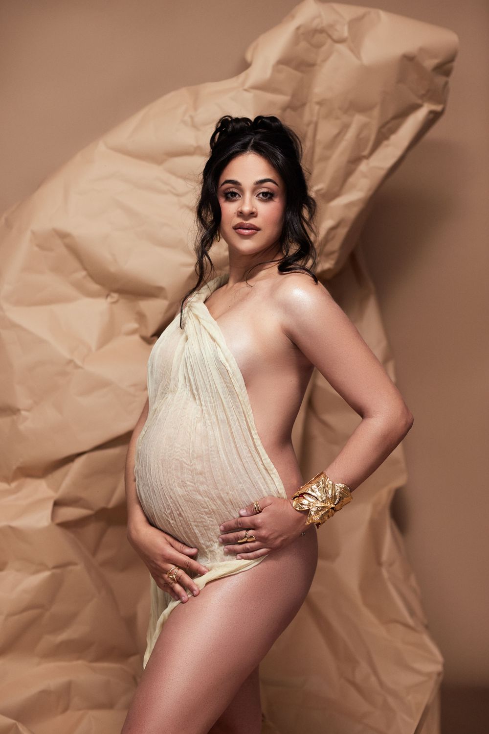 Maternity photo series showing pregnant figure in cream dress against textured brown paper backdrop.