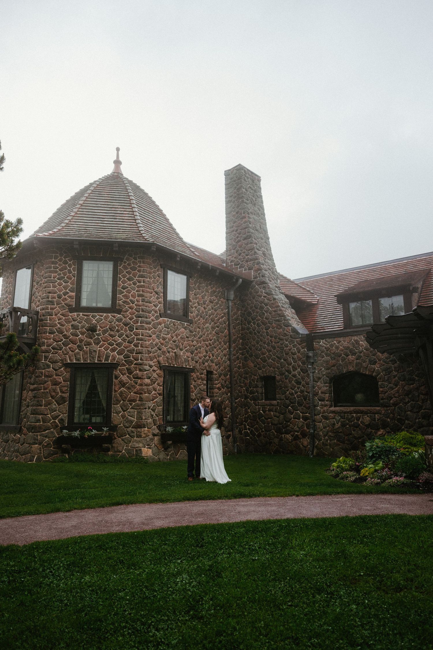 A stone castle-like building with multiple turrets and chimneys on a cloudy day.