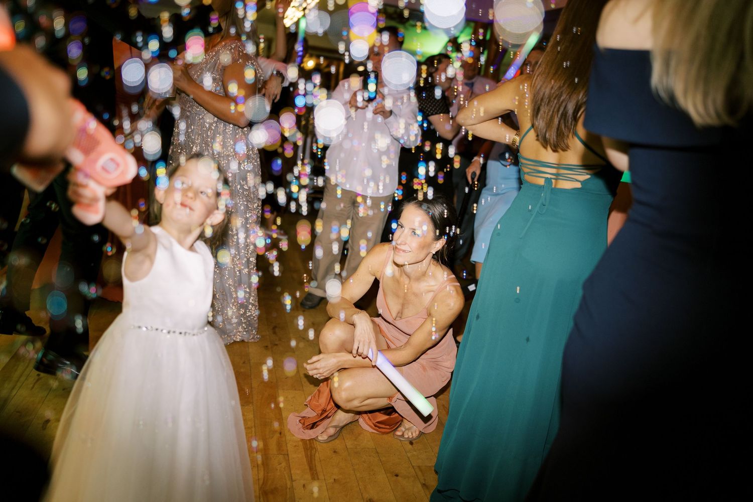 Wedding guests dancing and celebrating on a dance floor with confetti falling in the air at a reception party.