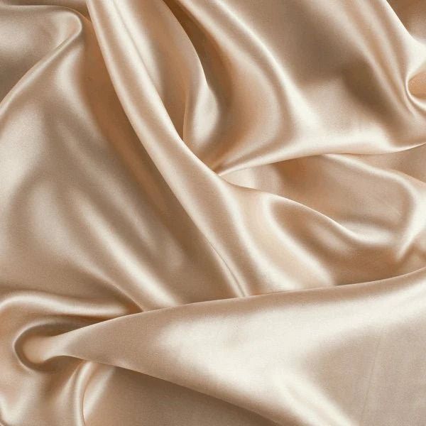 Smooth cream colored silk fabric with elegant folds and draping creating a luxurious satin texture.