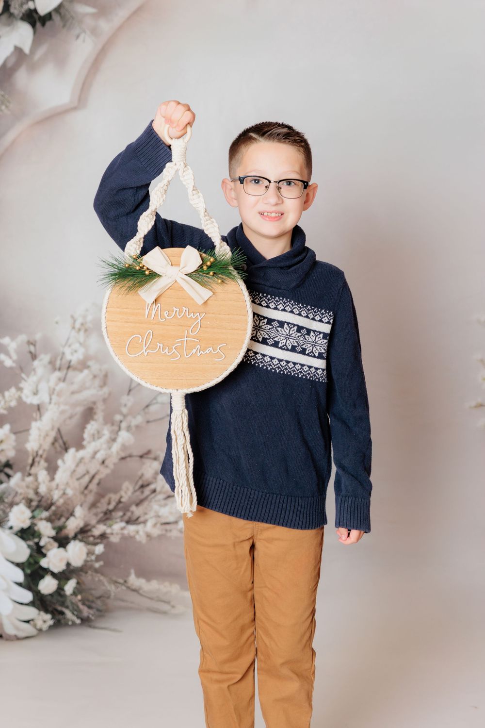 Young child in navy sweater and khaki pants poses with pumpkin sign against light gray studio backdrop. Clayton NJ Photo Studio