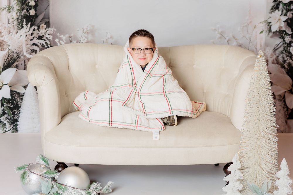 Cozy holiday scene with white sofa, flocked trees, and festive Christmas decorations in neutral tones. Clayton NJ Photo Studio