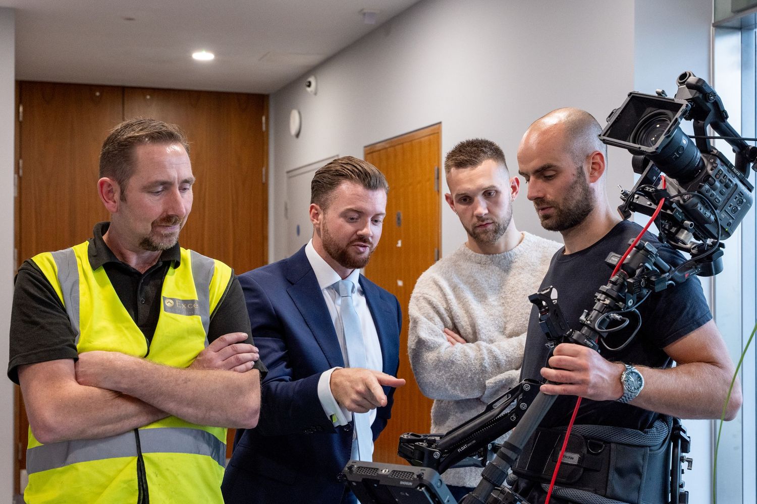 A group of people in a professional setting examining and working with camera equipment and technology.