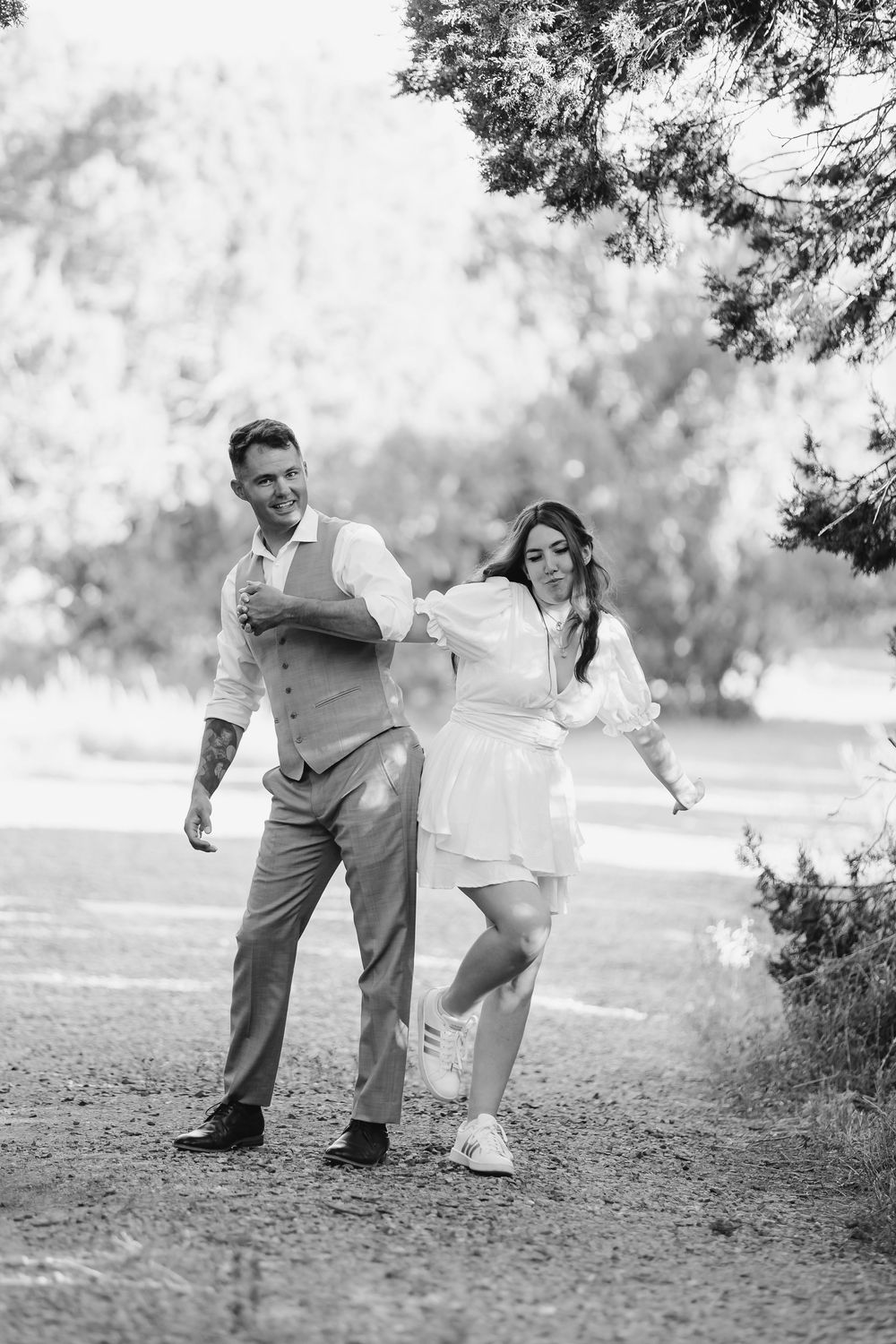 A couple in formal attire playfully poses in a sequence of black and white photos outdoors in a park setting.