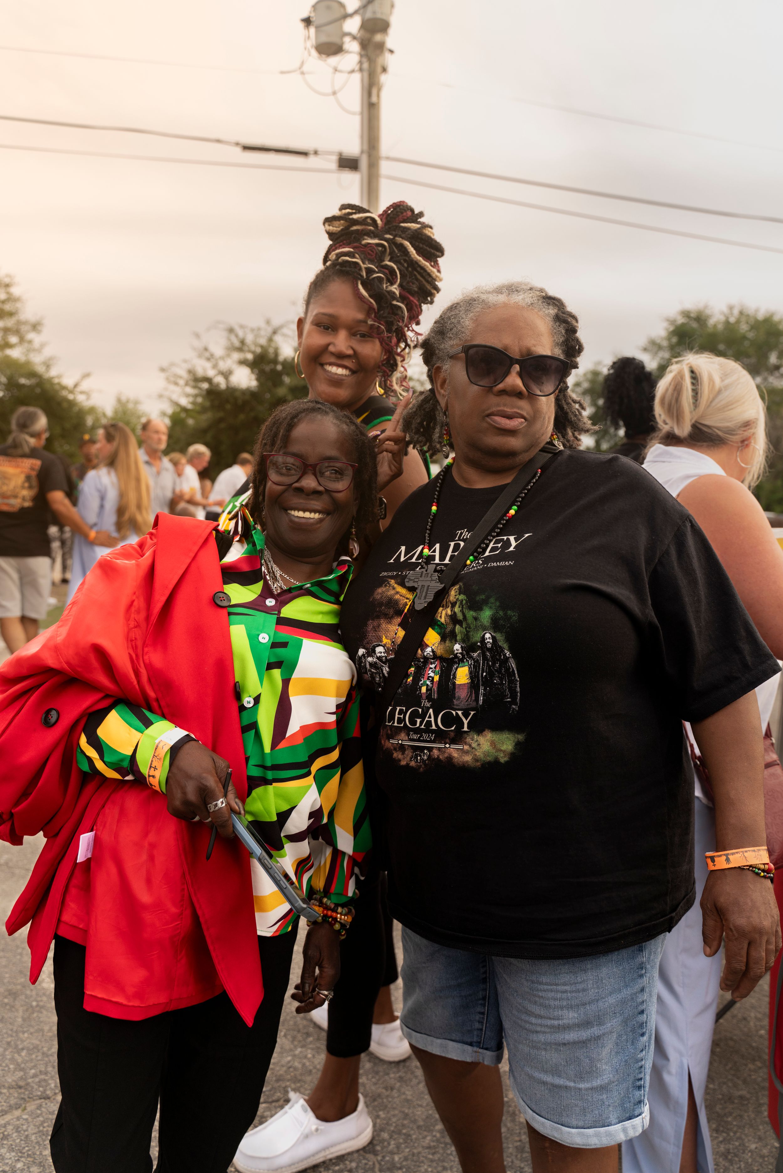 Friends enjoying a festive outdoor gathering wearing colorful Jamaican-themed clothing.