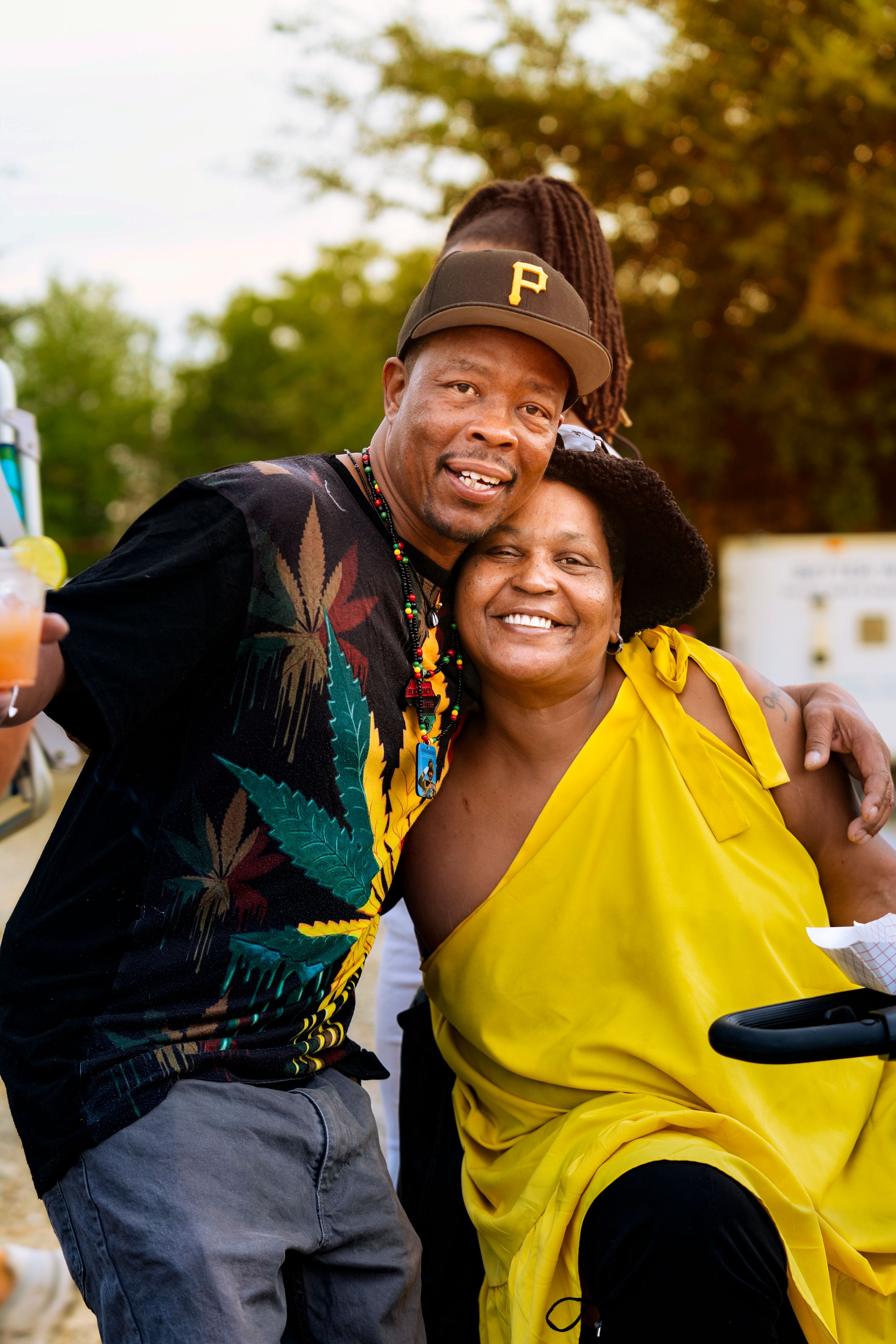 Two people in casual attire share a joyful embrace outdoors during golden hour lighting.