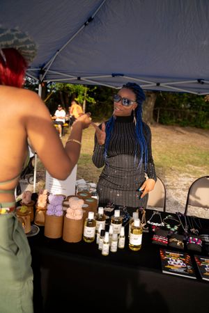 Bottles and beverages lined up at an outdoor vendor booth under a dark canopy.