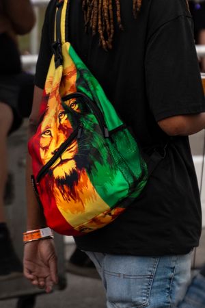 Colorful rasta-themed reusable shopping bag shown from different angles against dark clothing.