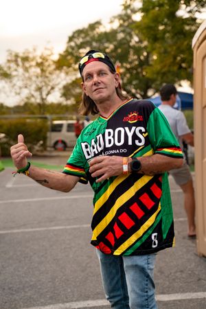 Person wearing a colorful reggae-style jersey with green and yellow stripes at an outdoor event.