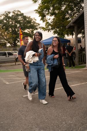 Group of people dancing and moving in a parking lot during an outdoor event.