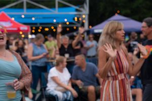 People dancing and enjoying an outdoor evening event with string lights and festive atmosphere.
