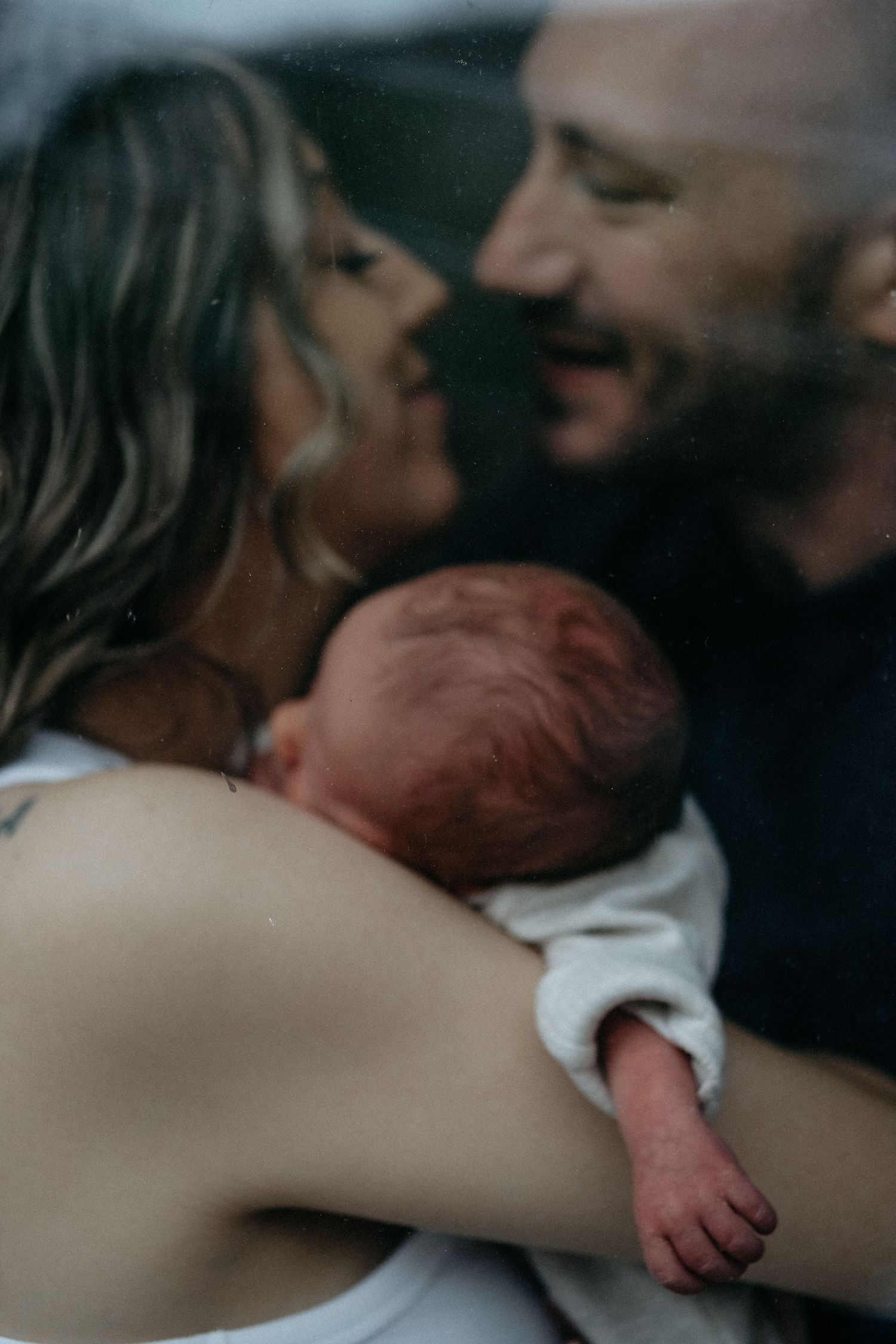 Parents cuddling their newborn baby during a tender early newborn lifestyle photography session in Blyth