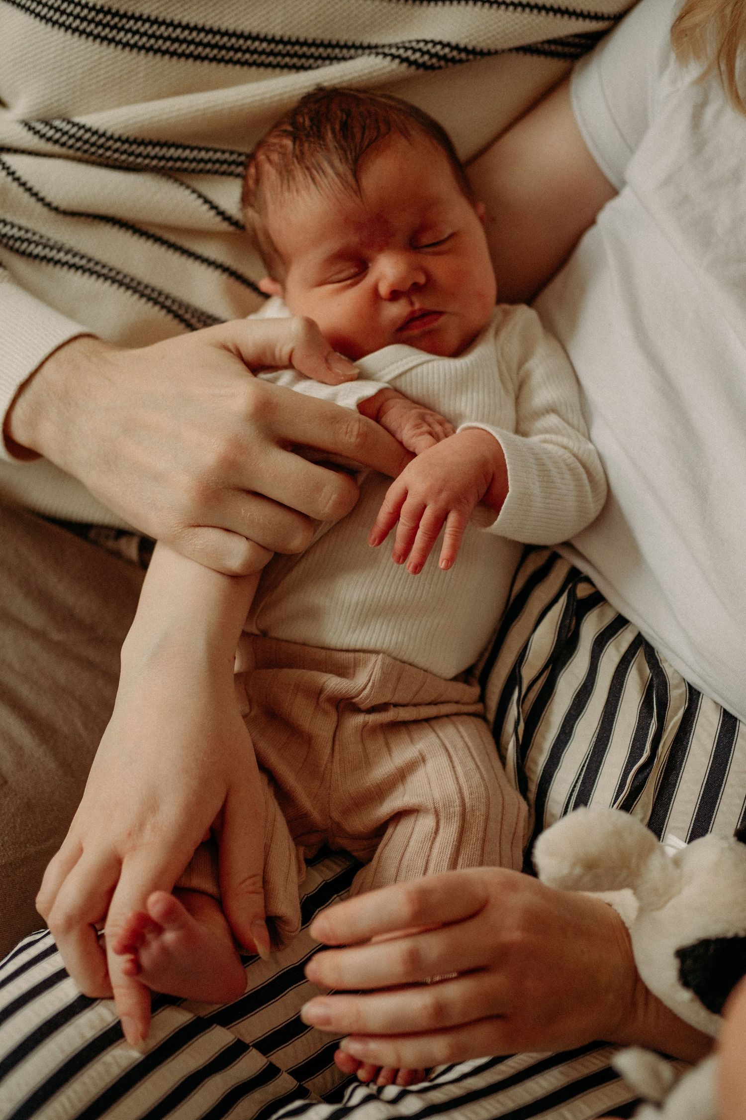 A newborn baby held in the arms of its parents in a newborn photo session in Monkseaton