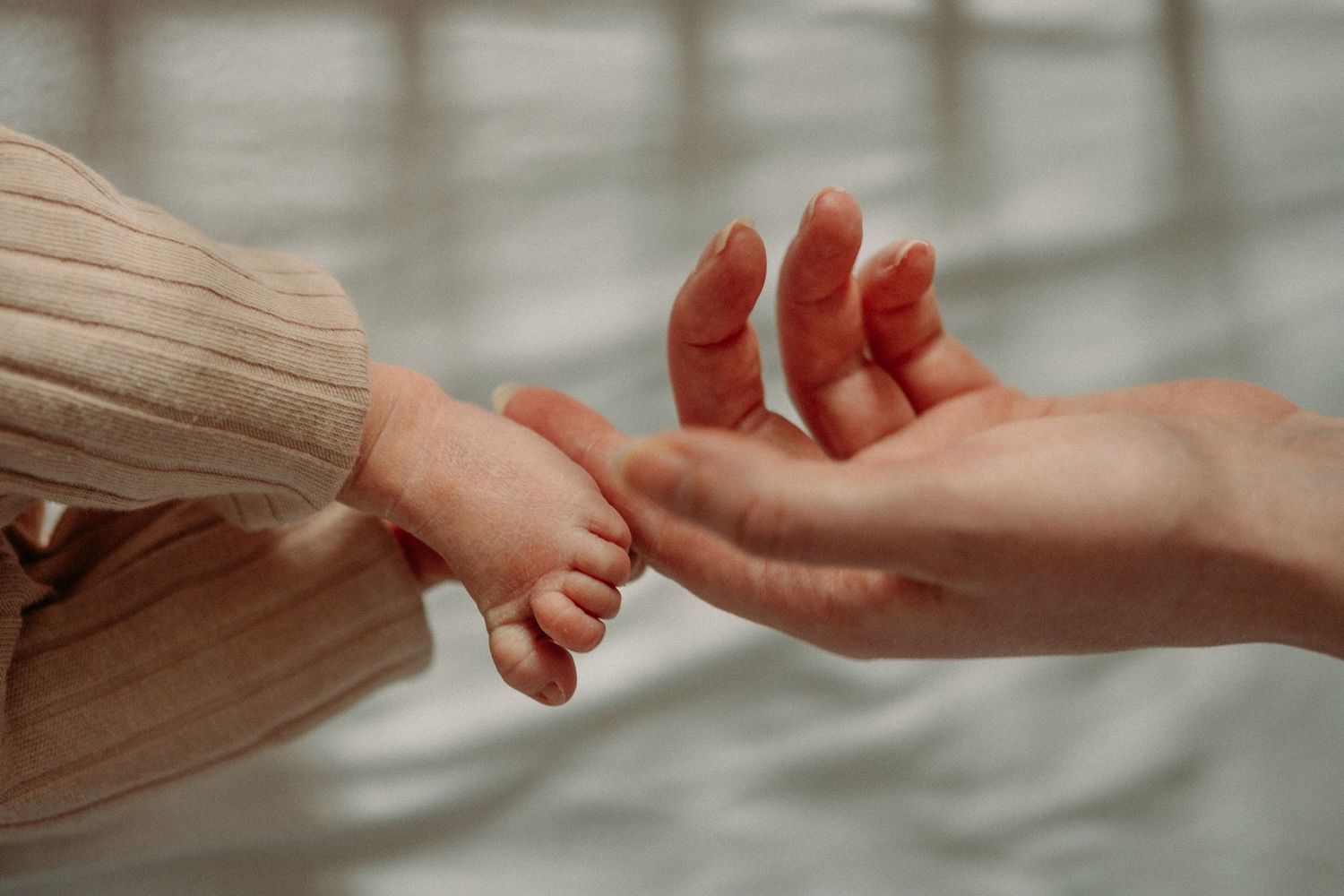 A mother gently caressing the foot of her newborn baby at a newborn shoot in Whitley bay
