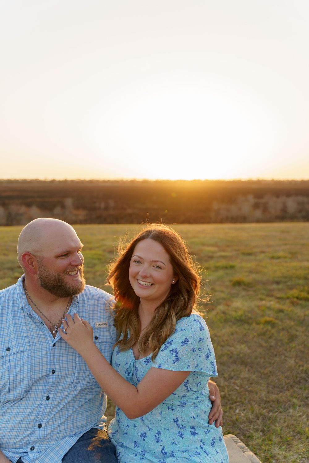 A couple shares an intimate moment in a field during golden hour wearing coordinating blue outfits.