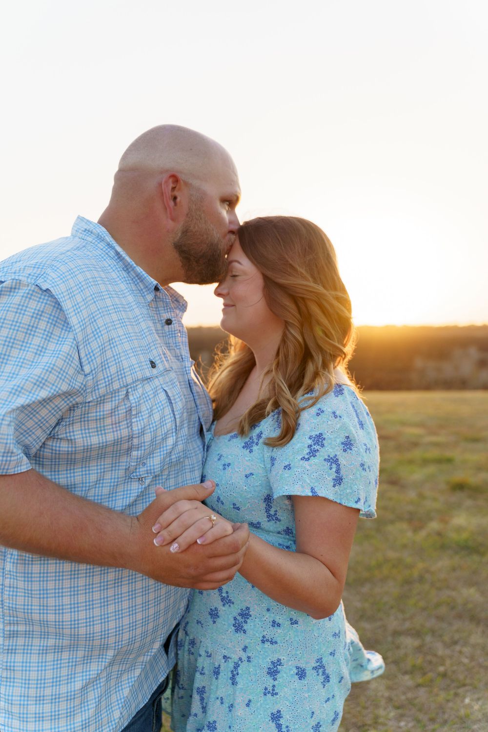 A tender moment between a couple in matching blue outfits as they share an intimate embrace at golden hour.