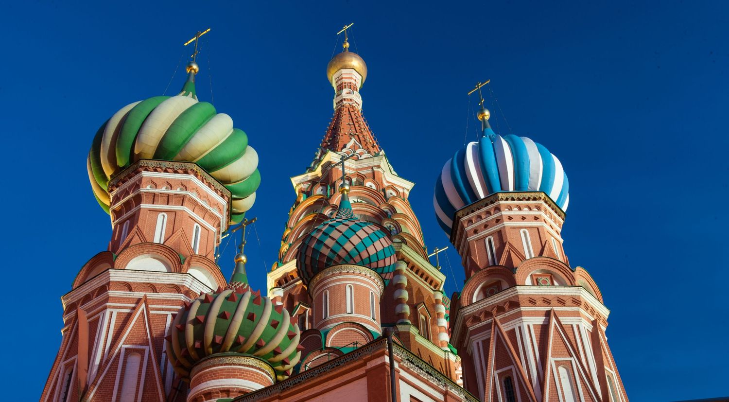 Colorful onion domes of Saint Basil's Cathedral against bright blue sky in Moscow, Russia.