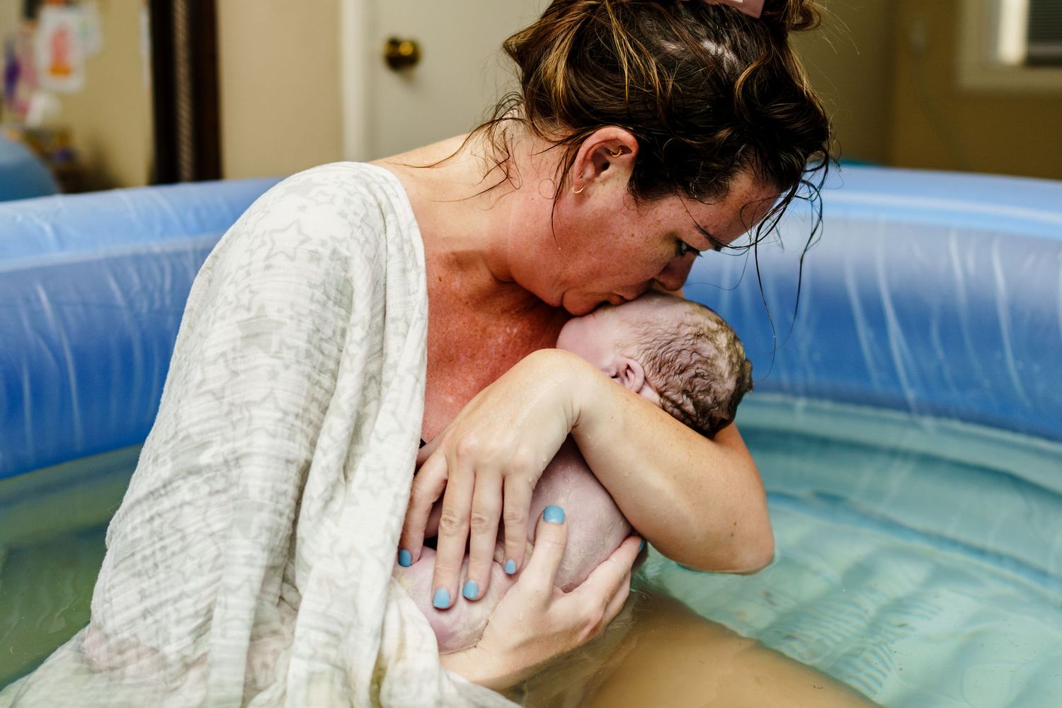 A photo showing a home water birth with a baby being delivered in a birthing pool shot by New Orleans Birth Photographer Autumn Hutton
