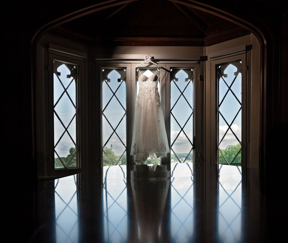 Gothic windows in a historic building frame a scenic countryside view with natural light streaming through.