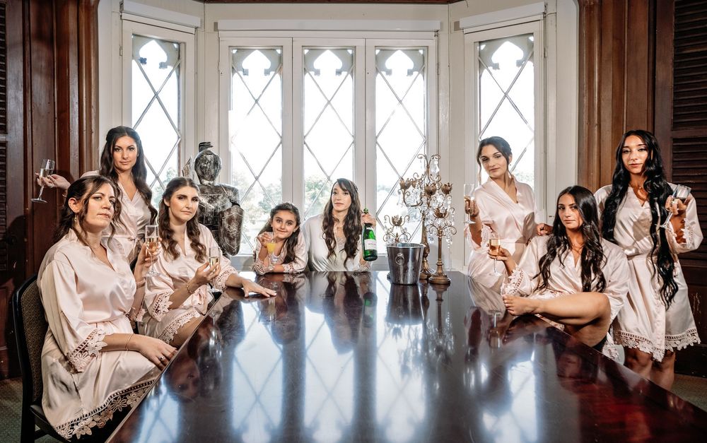 Wedding party members posing together in a bright room with elegant windows and natural lighting.