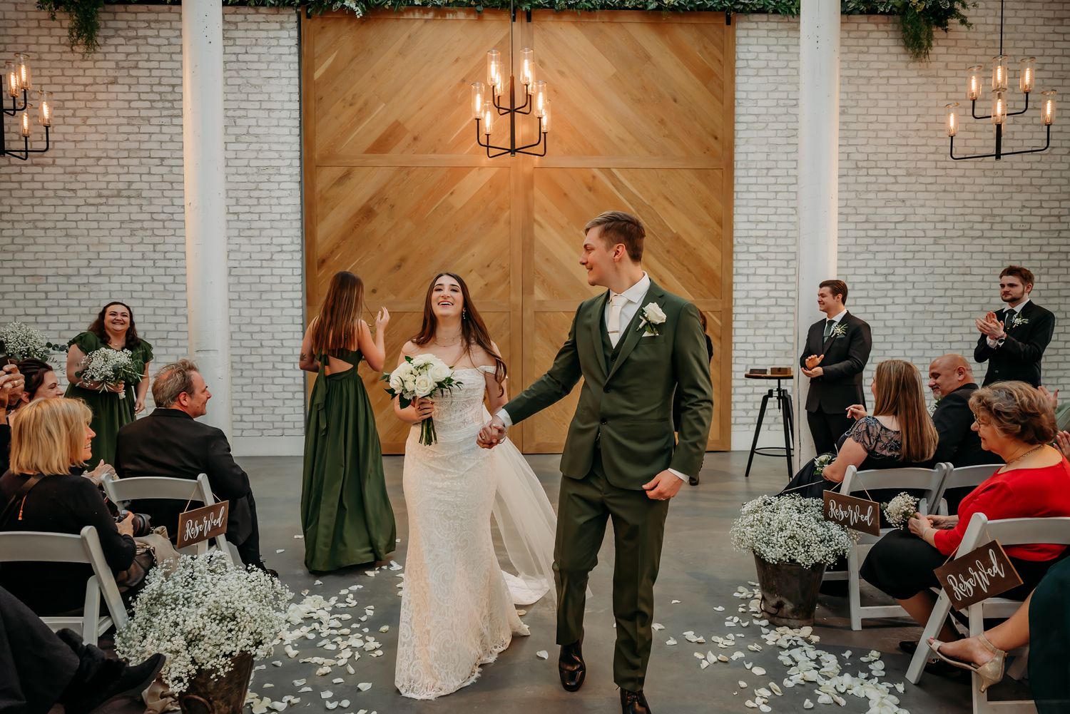 Wedding ceremony in modern chapel with brick walls and wooden backdrop as couple walks down aisle.