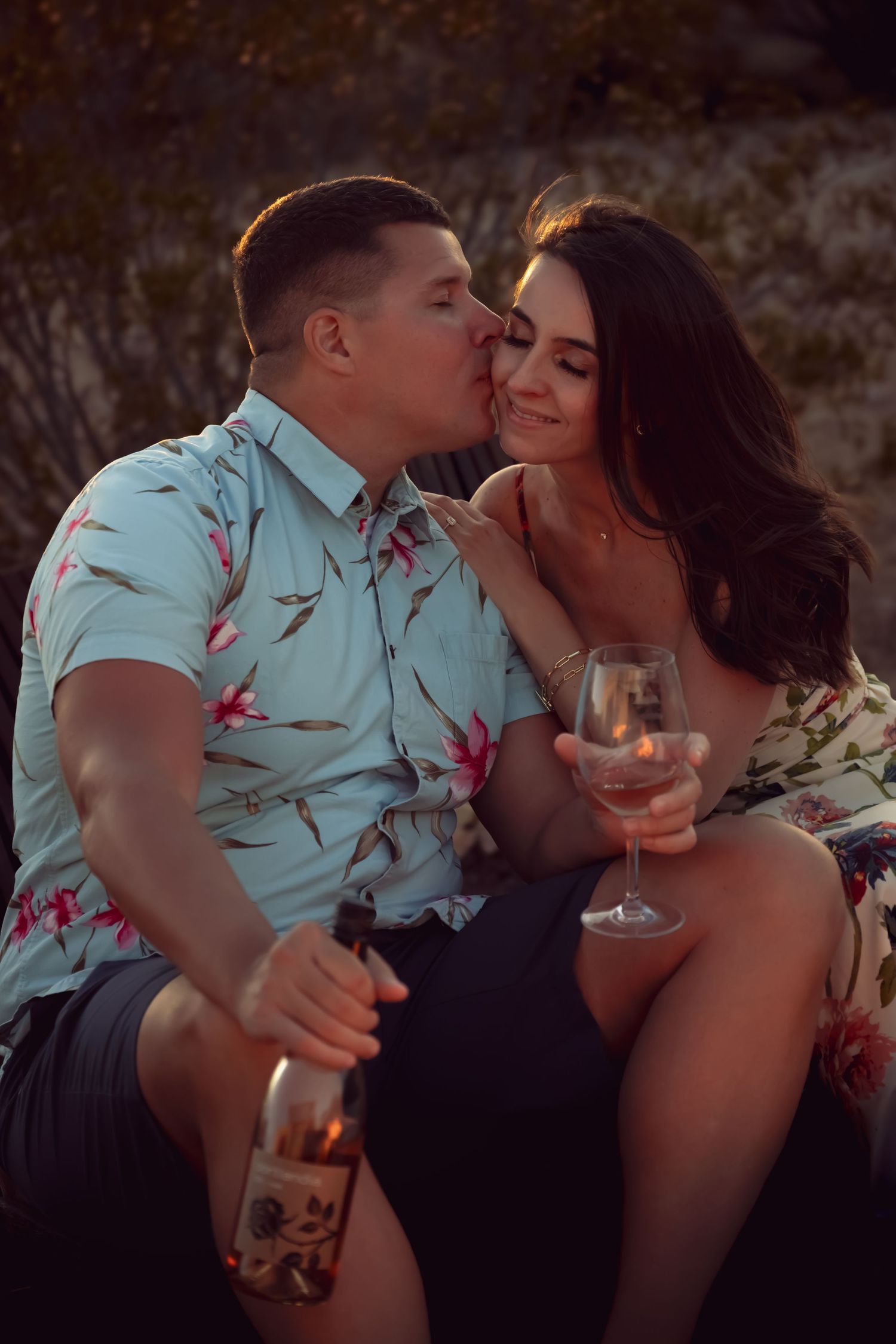 Couple sharing intimate moment with wine glasses at sunset.