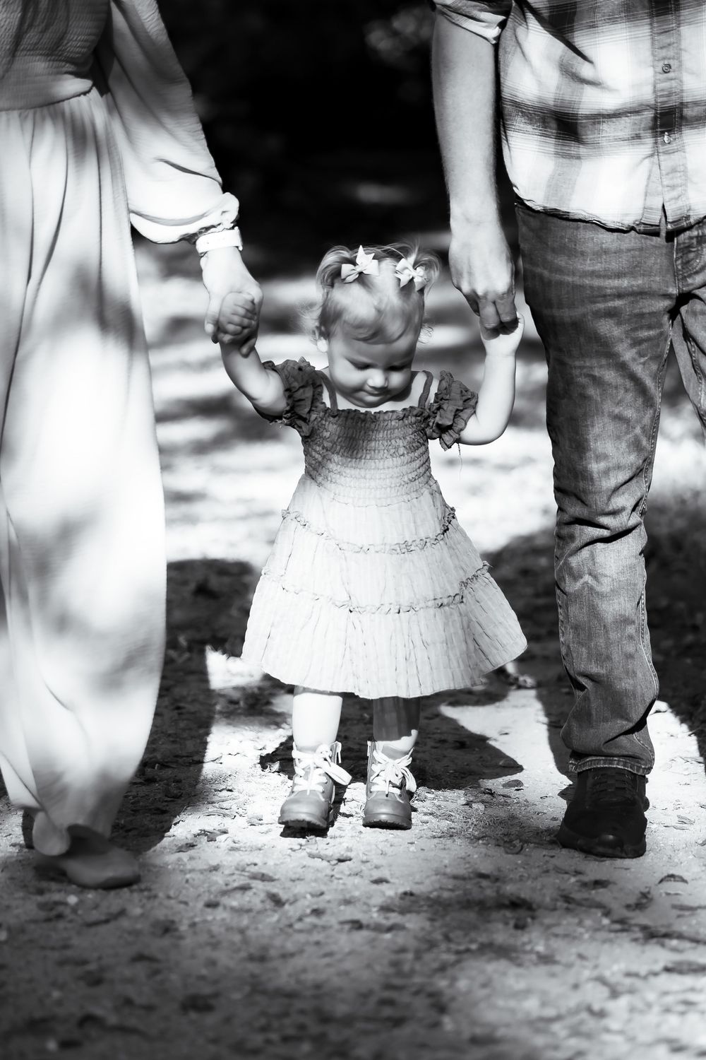 Black and white photo of family feet and legs standing together on dirt path.