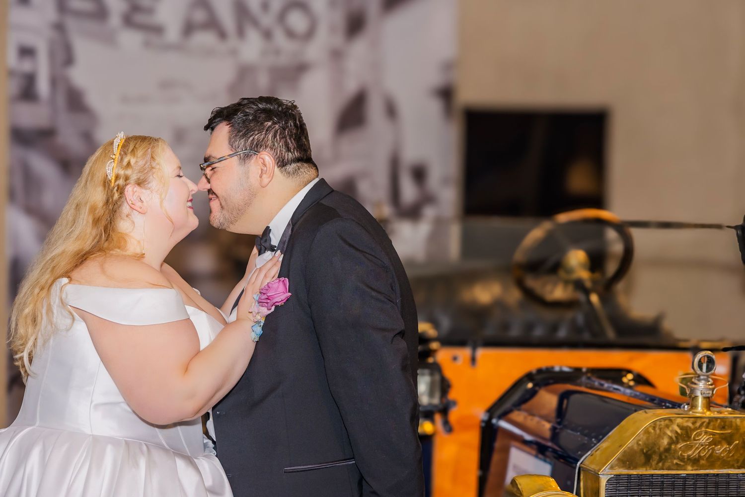 A couple shares a romantic kiss during their wedding reception in a warmly lit venue.