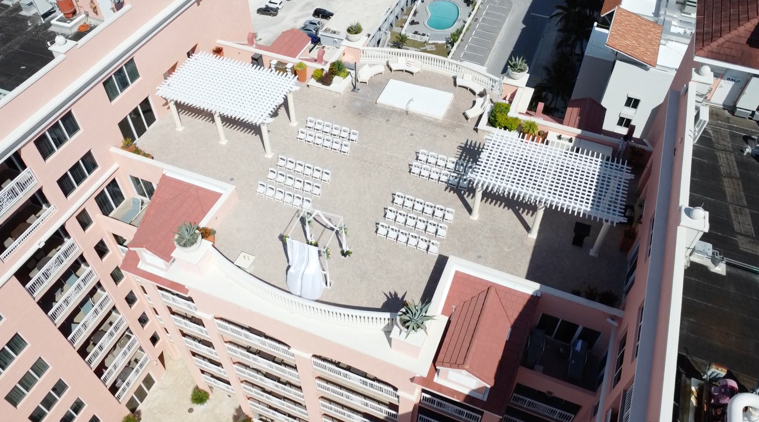 Aerial view of a resort rooftop deck with white chairs set up for an outdoor event.