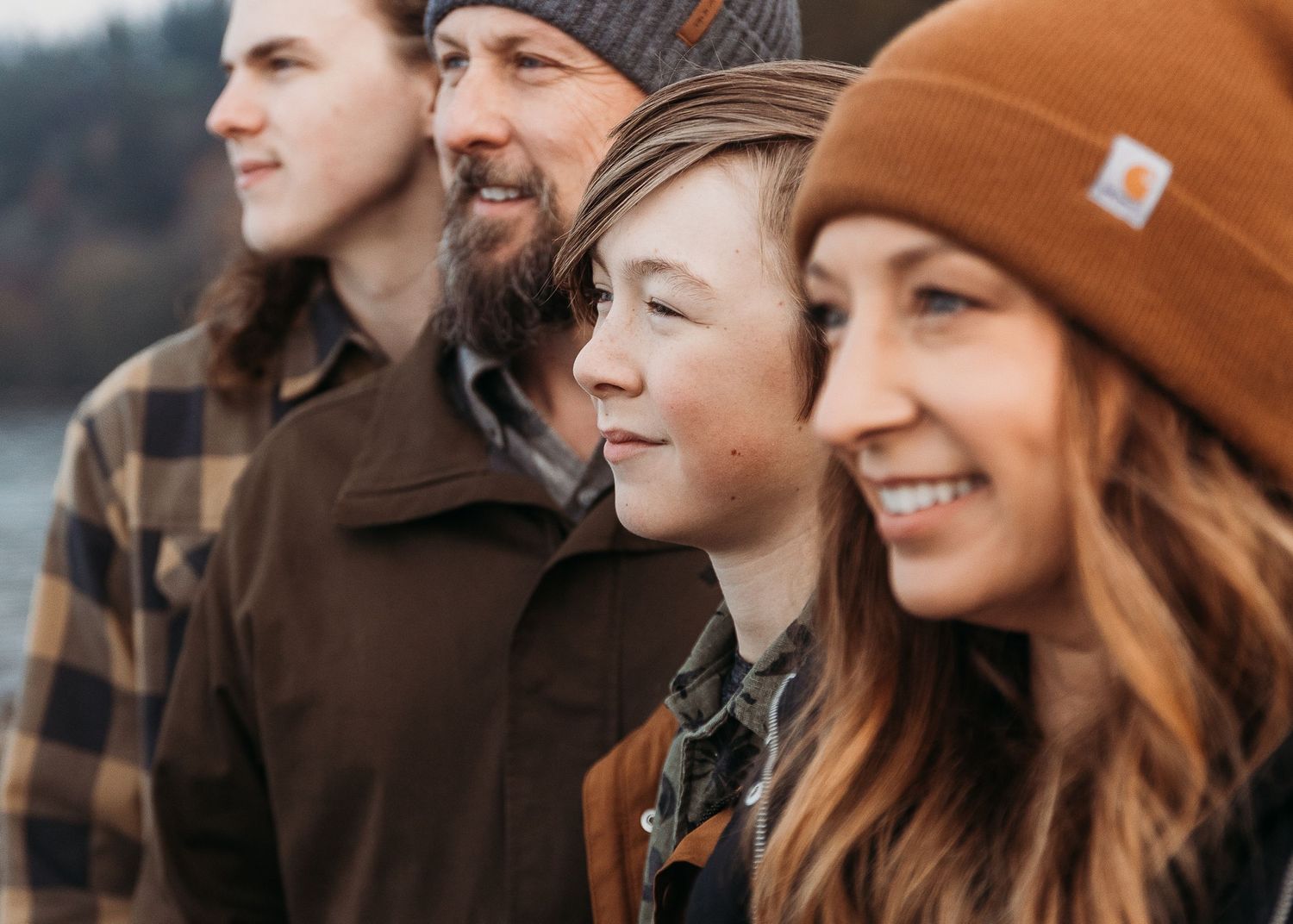 Group wearing winter hats standing together on a cloudy day.