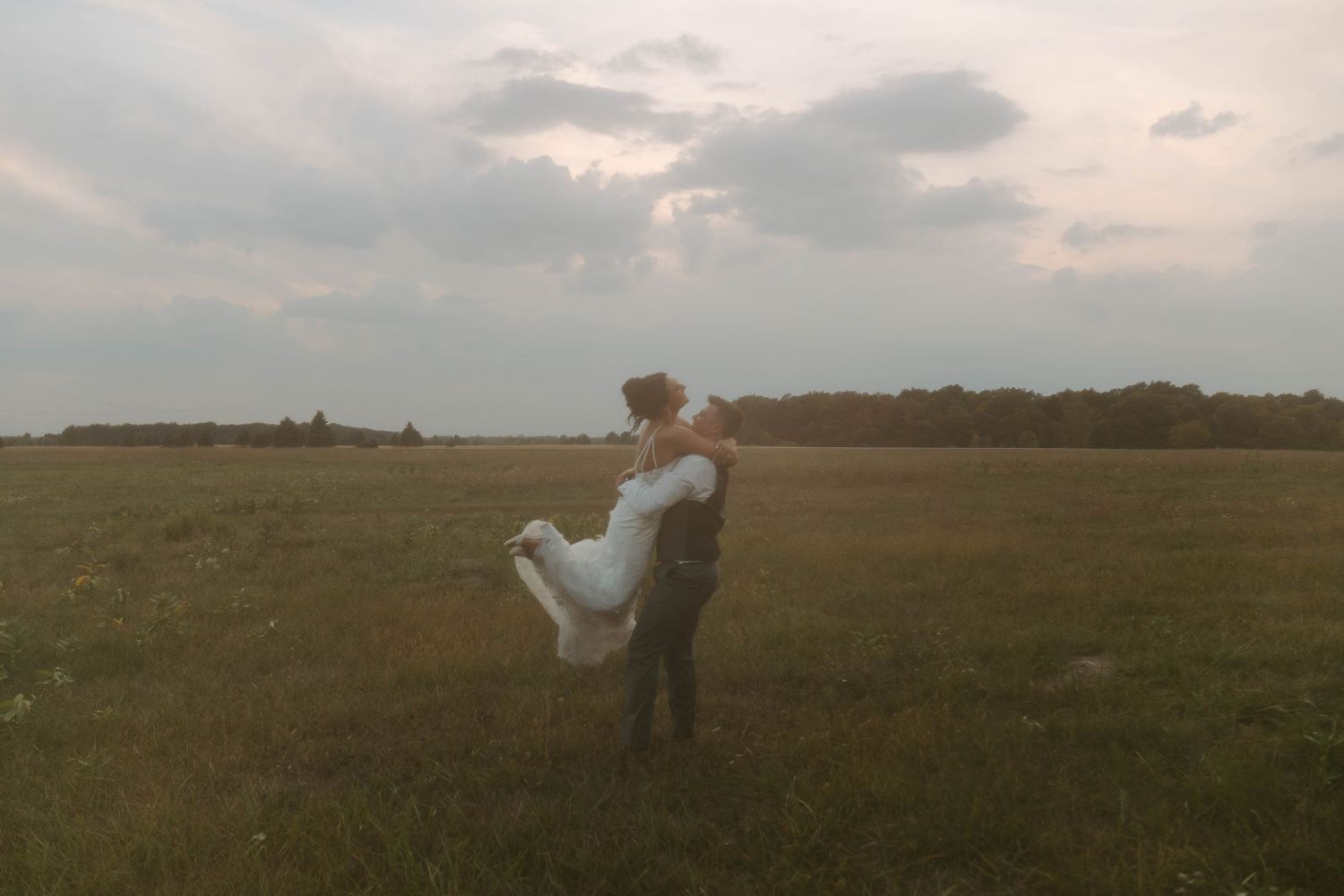 A couple walking through a sunlit field at golden hour.