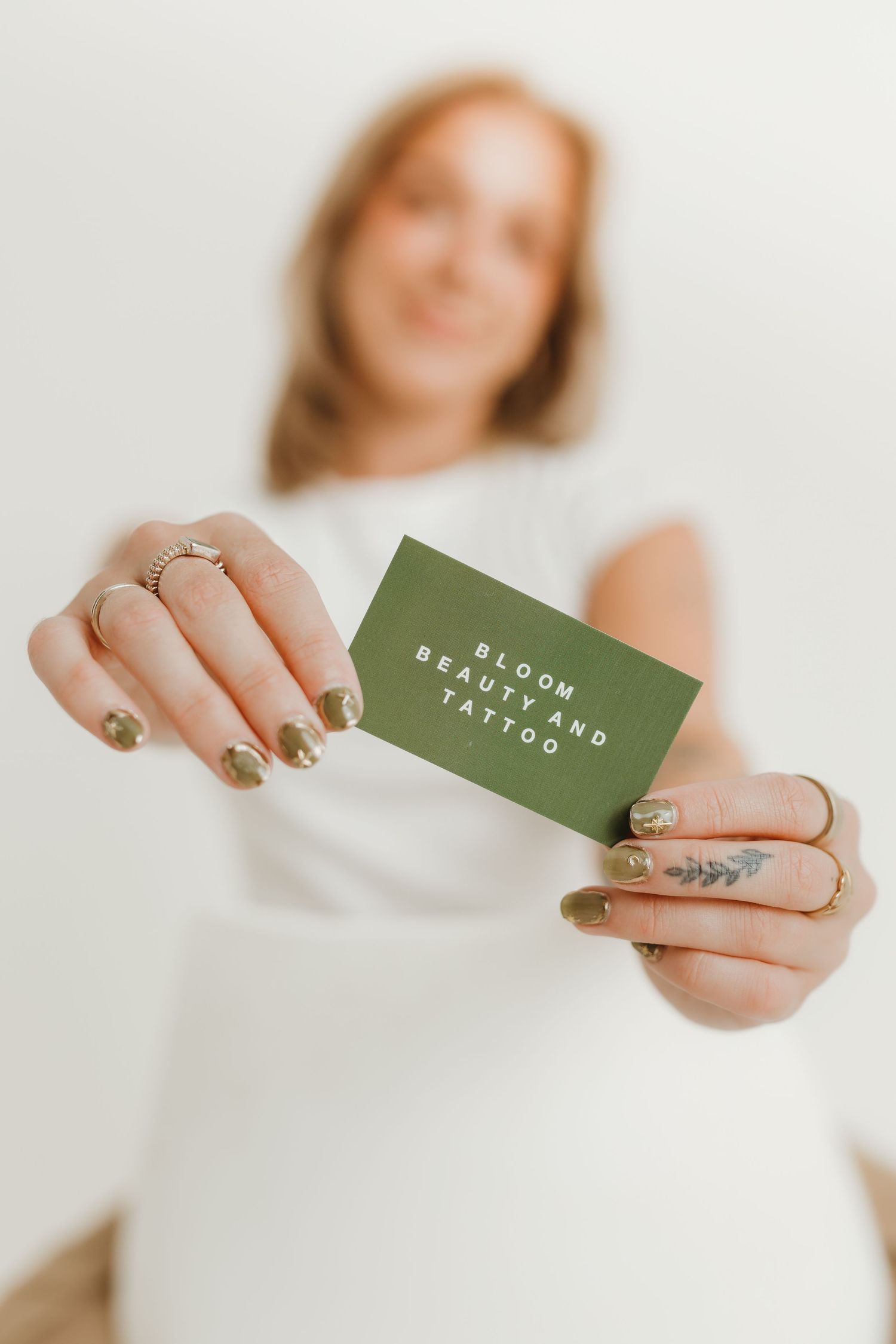 Close-up of hands with green business card showing stylish nail art andjewelry.
