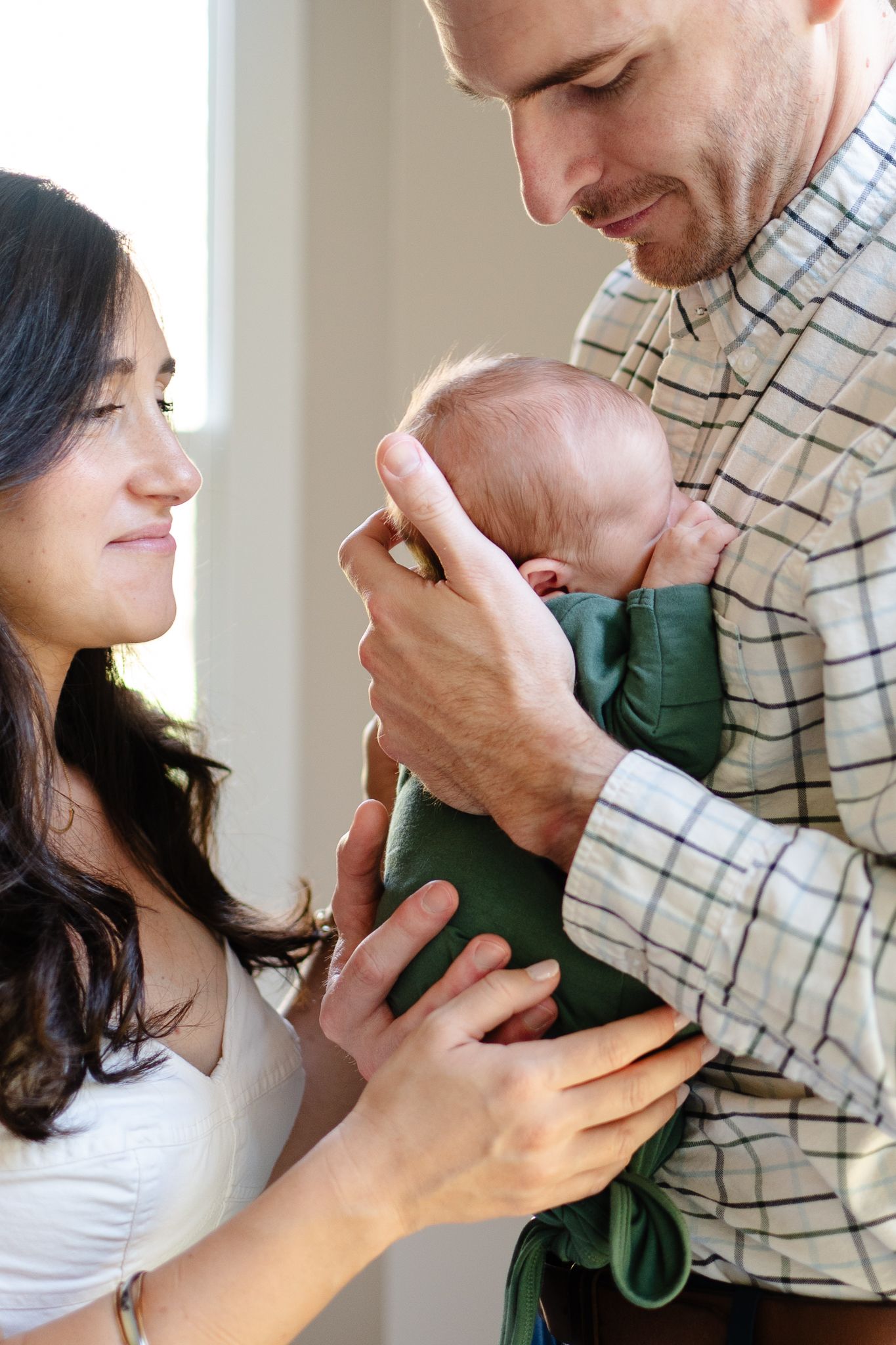 Mom and Dad hold baby during their newborn shoot at home.