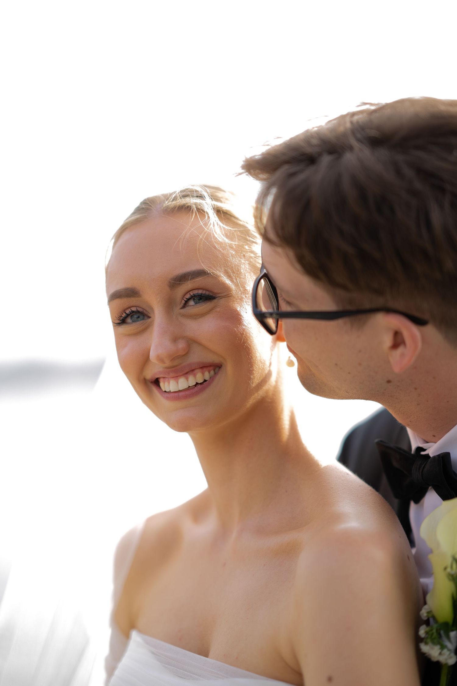 Joyful wedding moment captured in golden sunlight by the water.