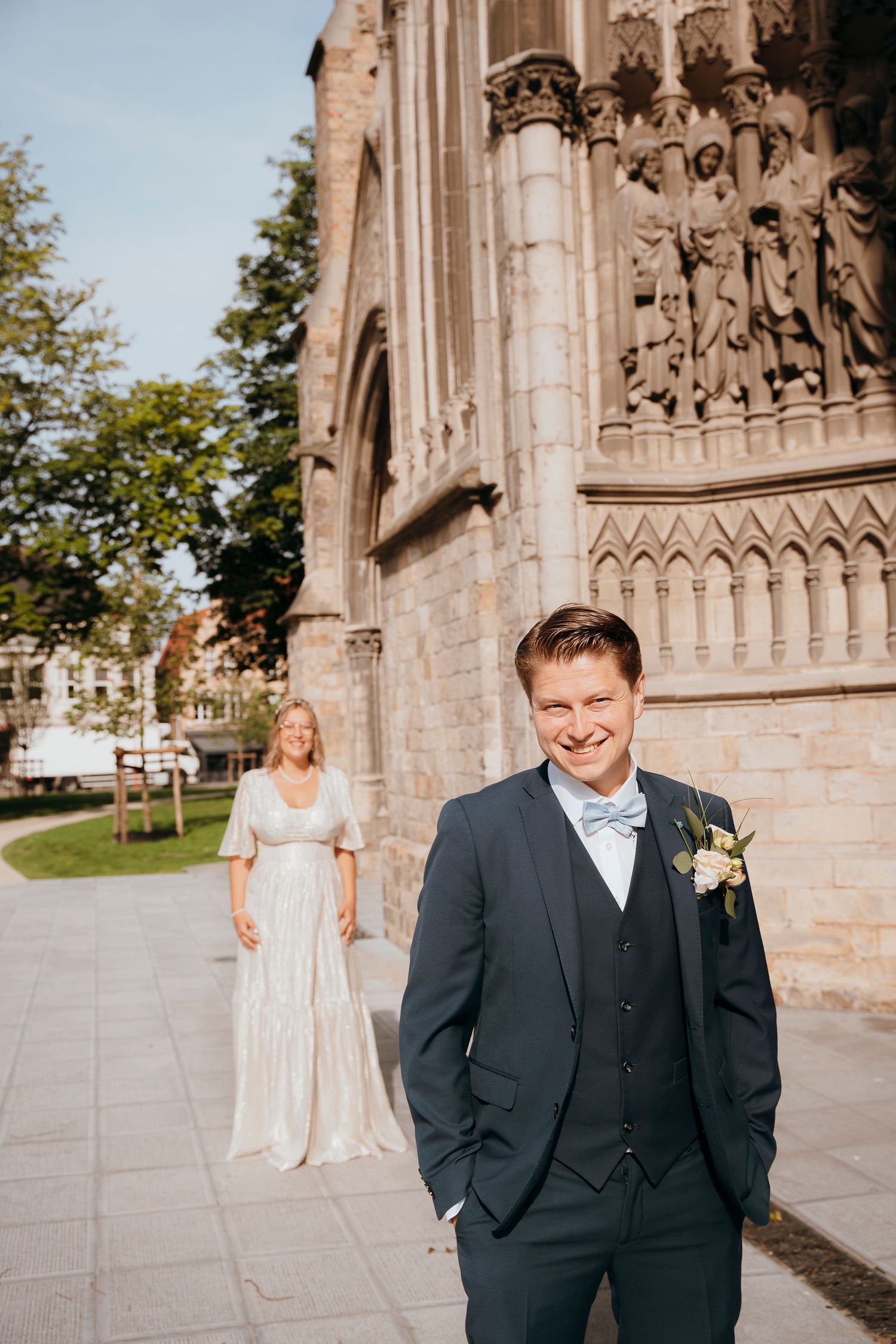 A first look wedding moment outside a historic Gothic cathedral with ornate stone details.