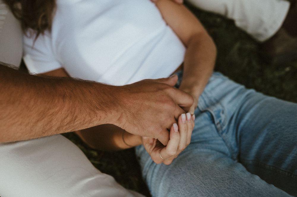 Close-up of hands clasped together on casual denim jeans.