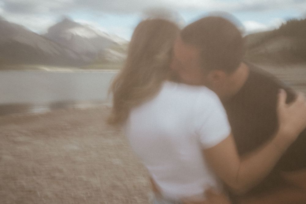 Dreamy blurred silhouettes embracing against mountain backdrop.