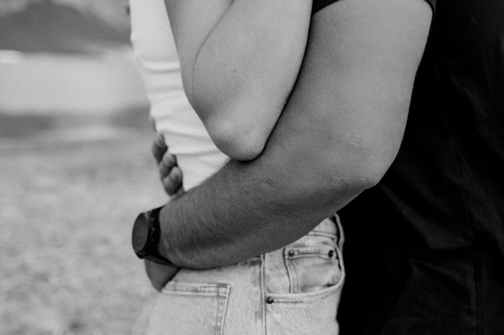 Black and white close-up of intimate embrace showing denim and white clothing.