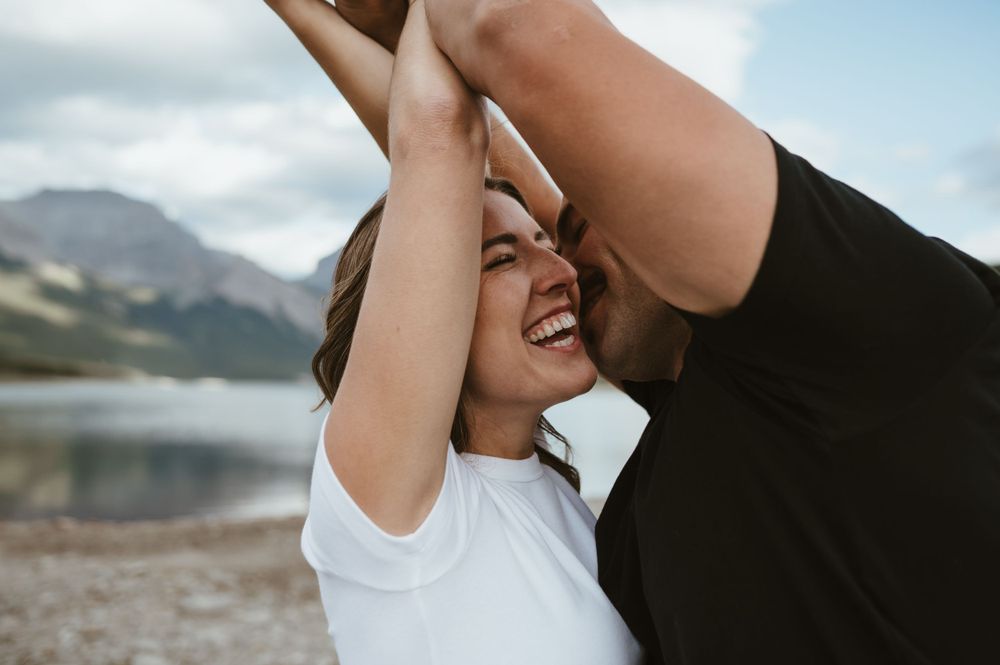 Joyful moment shared against scenic mountain lake backdrop.