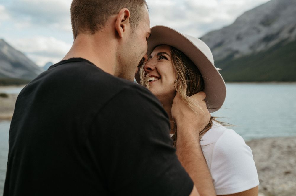 Intimate couple sharing a tender moment against a backdrop of mountains and a serene lake.
