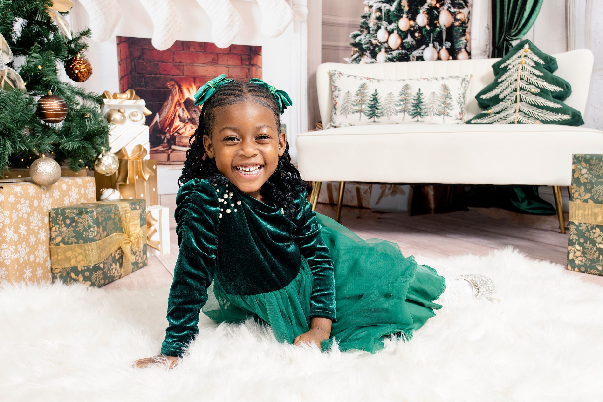Holiday photo setup with green velvet curtains and decorated Christmas trees.