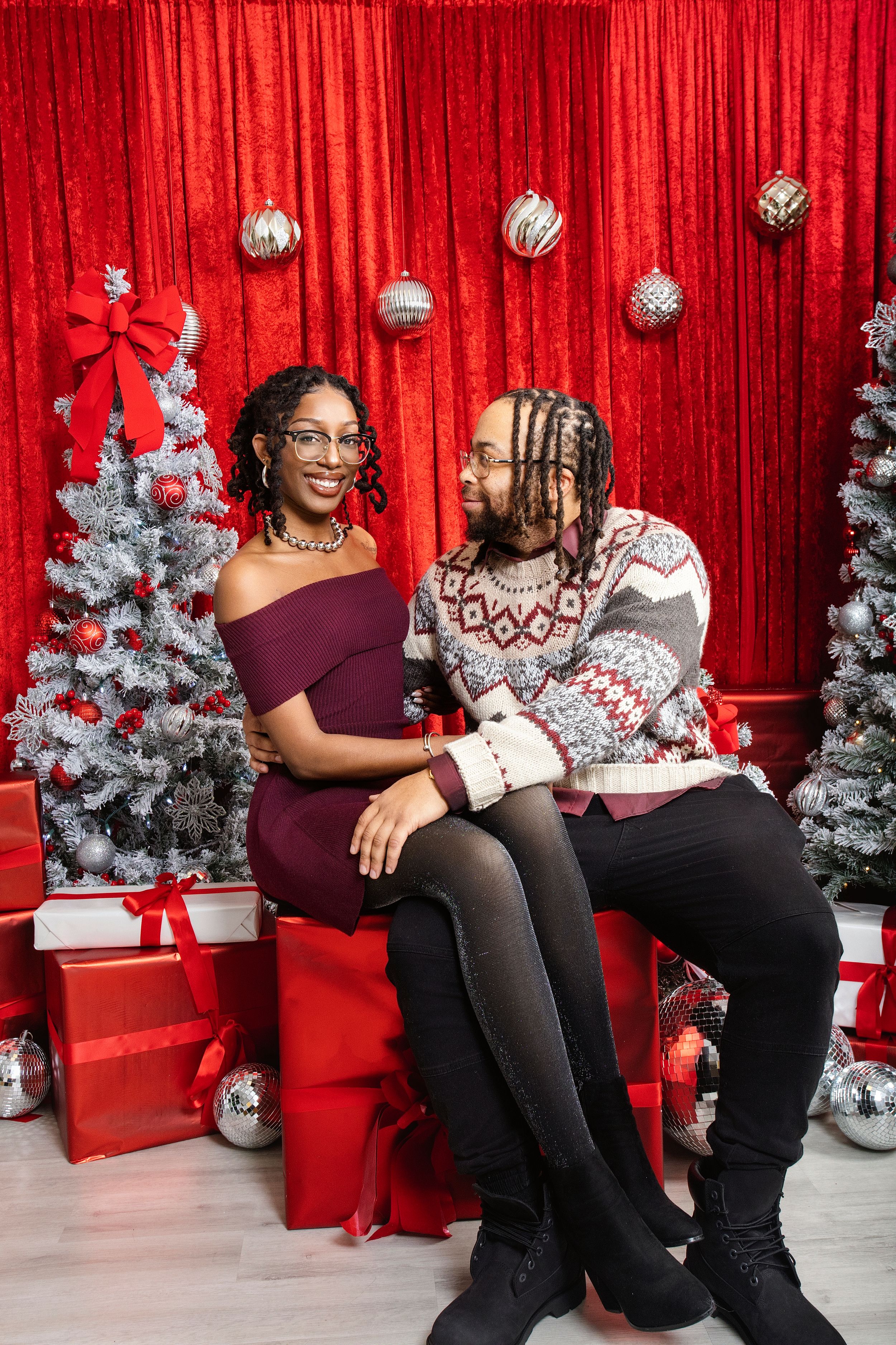 Family Christmas portrait with silver trees and festive red decor.