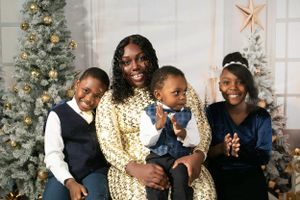 Family in coordinated navy and gold outfits poses by decorated Christmas tree with star ornaments.