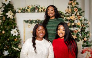 Family members wearing red and white sweaters pose together in front of a decorated Christmas tree.