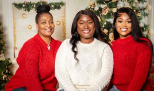 Group photo of people wearing coordinated holiday sweaters in front of a Christmas tree.