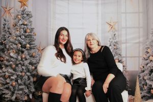 Holiday portrait setup with decorated Christmas trees and rose gold star decorations in a bright studio.