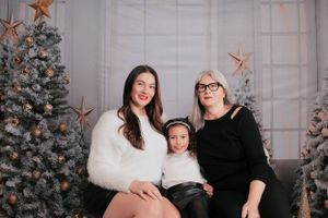 Family holiday portrait with Christmas decorations and a flocked tree in the background.