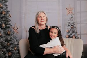 Festive holiday portrait with decorated Christmas trees and copper star decorations in background.