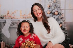 Cozy holiday portrait with decorated Christmas tree and stockings in background.