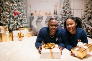 Couple in matching blue outfits smiling with Christmas presents.